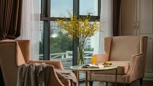 Ein modernes Zimmer mit großem Fenster, einer Vase mit gelben Blumen, einem Tisch mit einem Buch und einem Glas Orangensaft sowie zwei Stühlen.