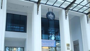 Ein Hotel Eingang mit Glasfassade, einem Schild mit der Aufschrift "AODONIS HOTEL" und der Zahl "55" an der Wand.