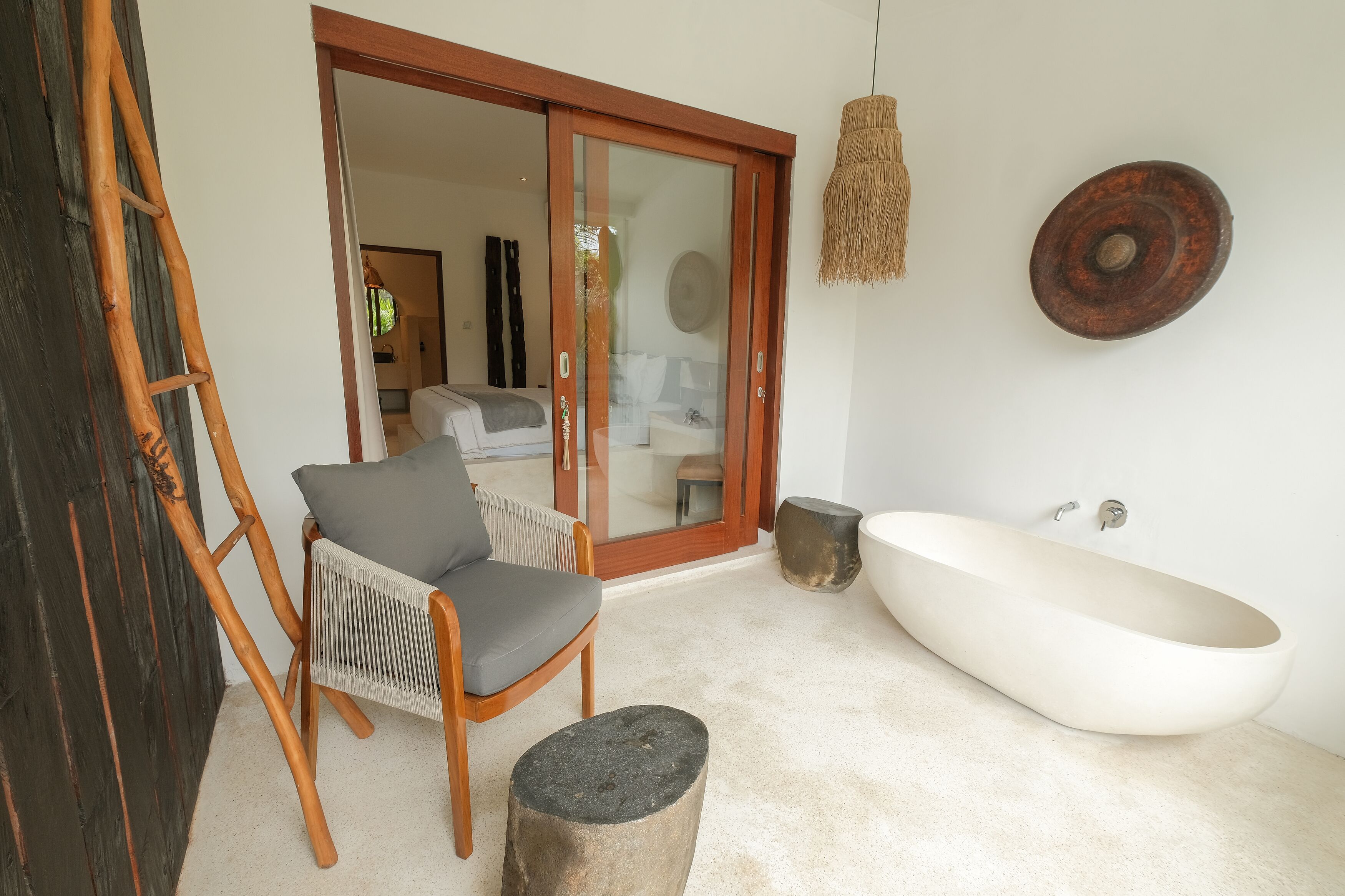 A bathroom with a freestanding bathtub, a wooden chair, and a large mirror.
