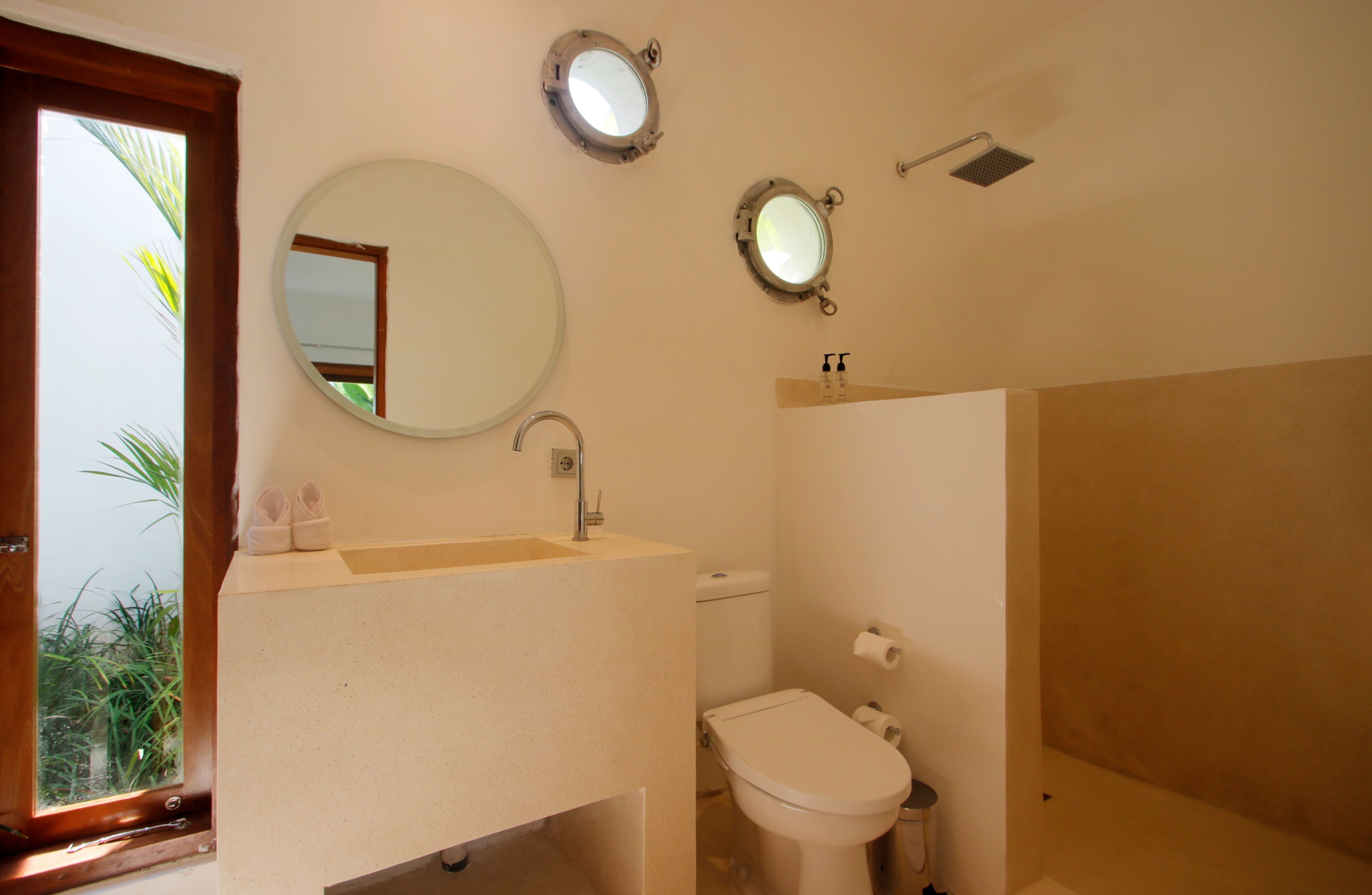 A bathroom with a sink, toilet, and two mirrors.