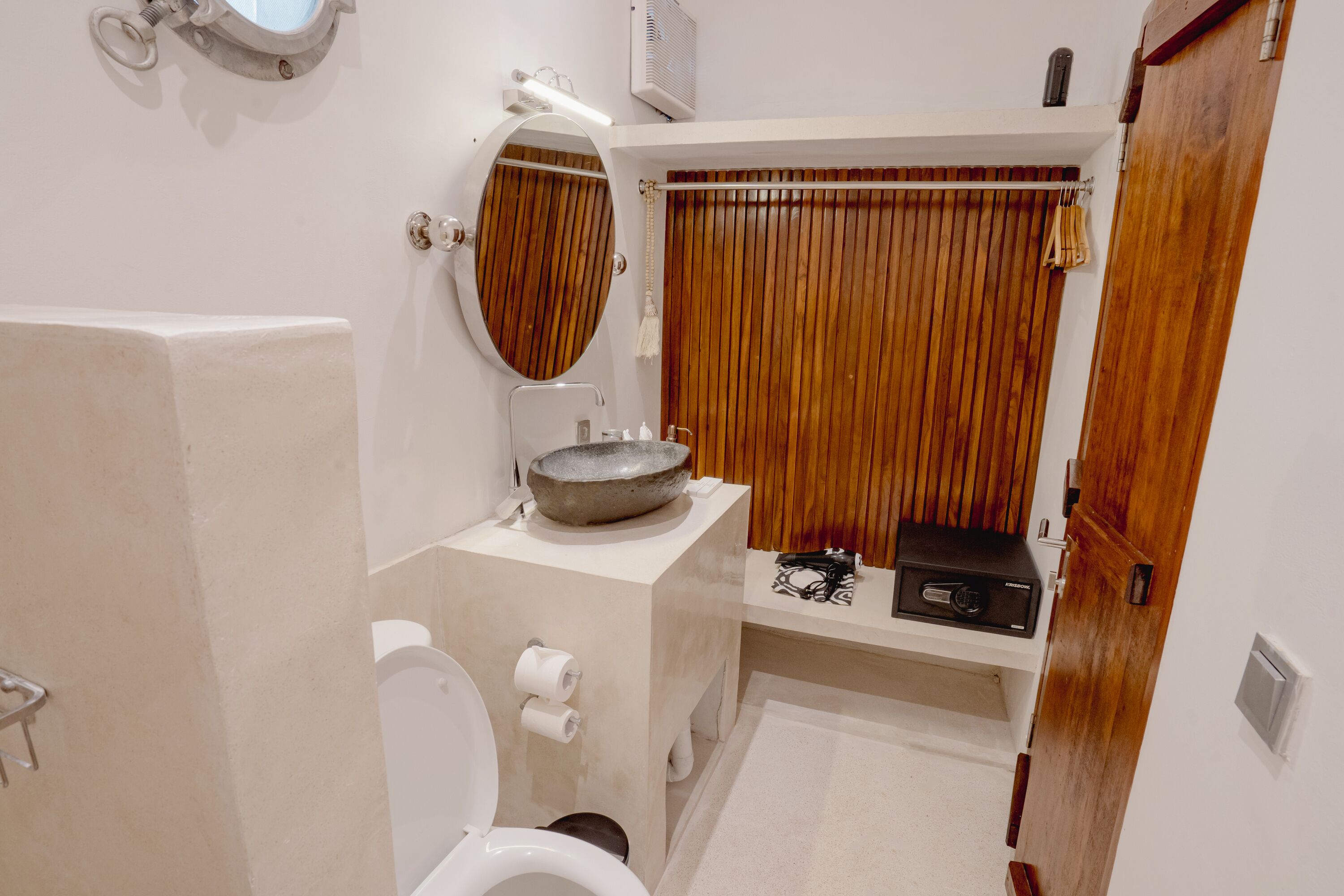 Een badkamer met toilet, wastafel, spiegel en een wand van hout.