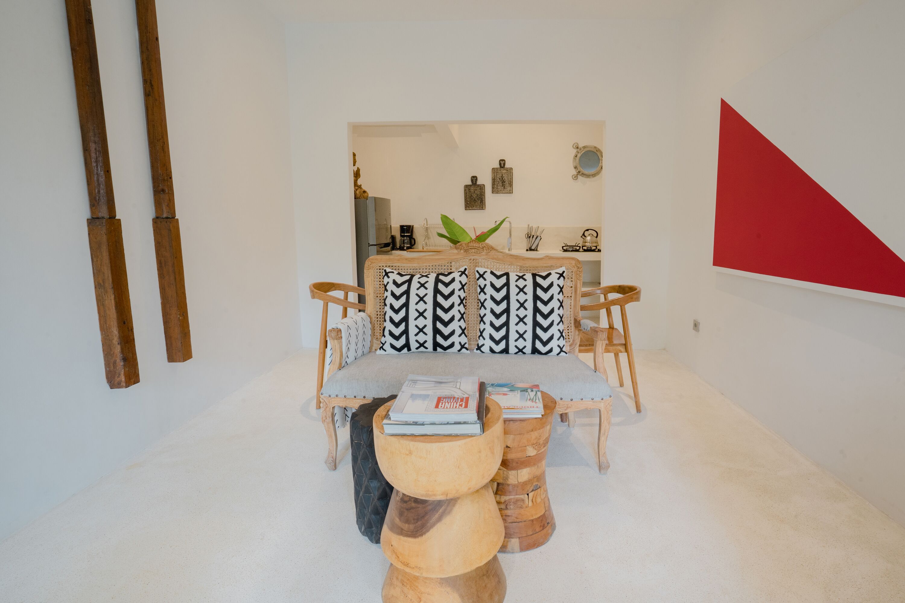 A dining area with a table set for two, surrounded by wooden chairs and a unique, multi-tiered wooden stool.
