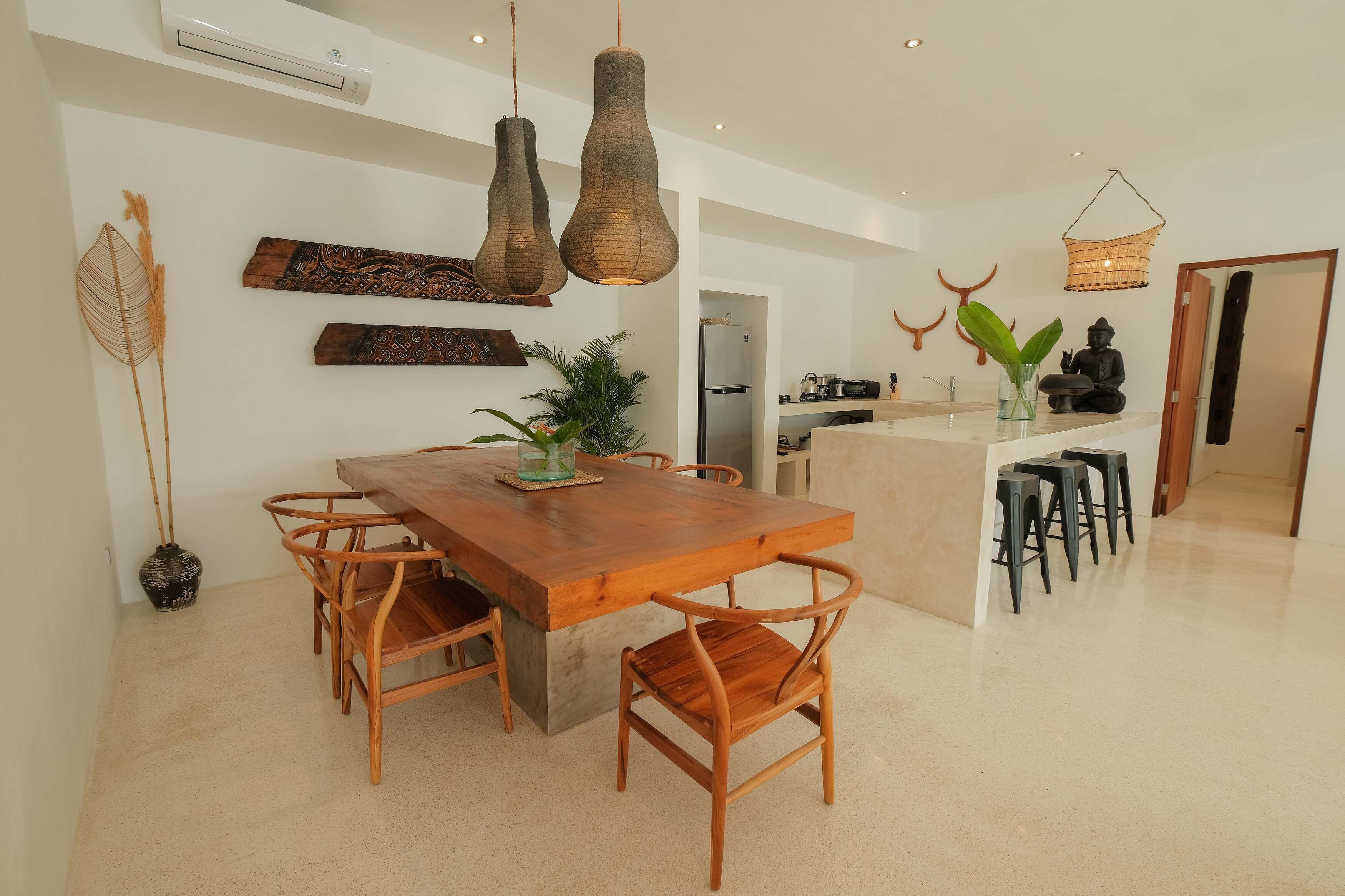 A modern kitchen with a wooden dining table and chairs, a hanging light fixture, and a small island with stools.