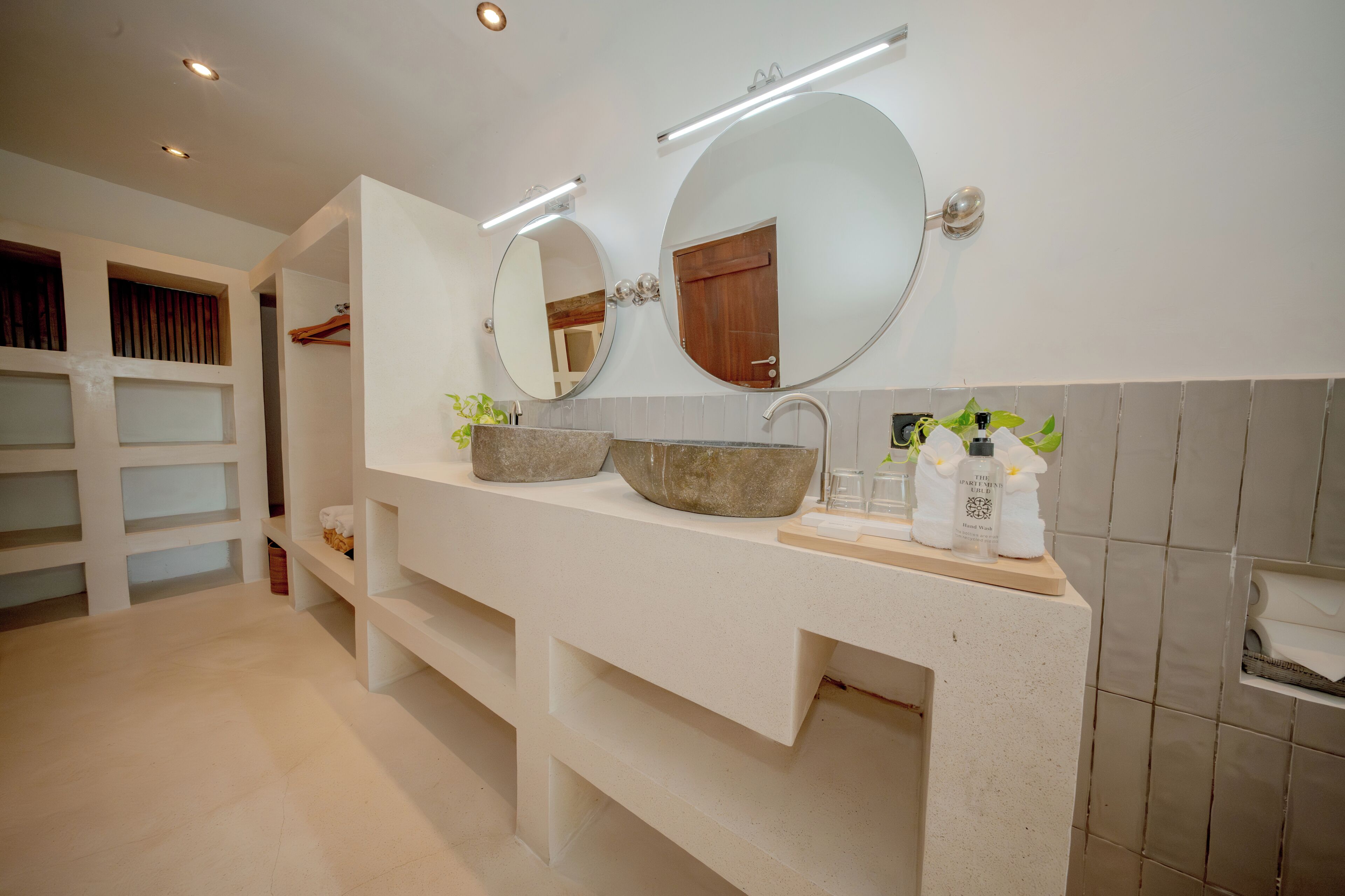 A modern bathroom with a large vanity, two mirrors, a sink with a stone basin, and a towel rack.