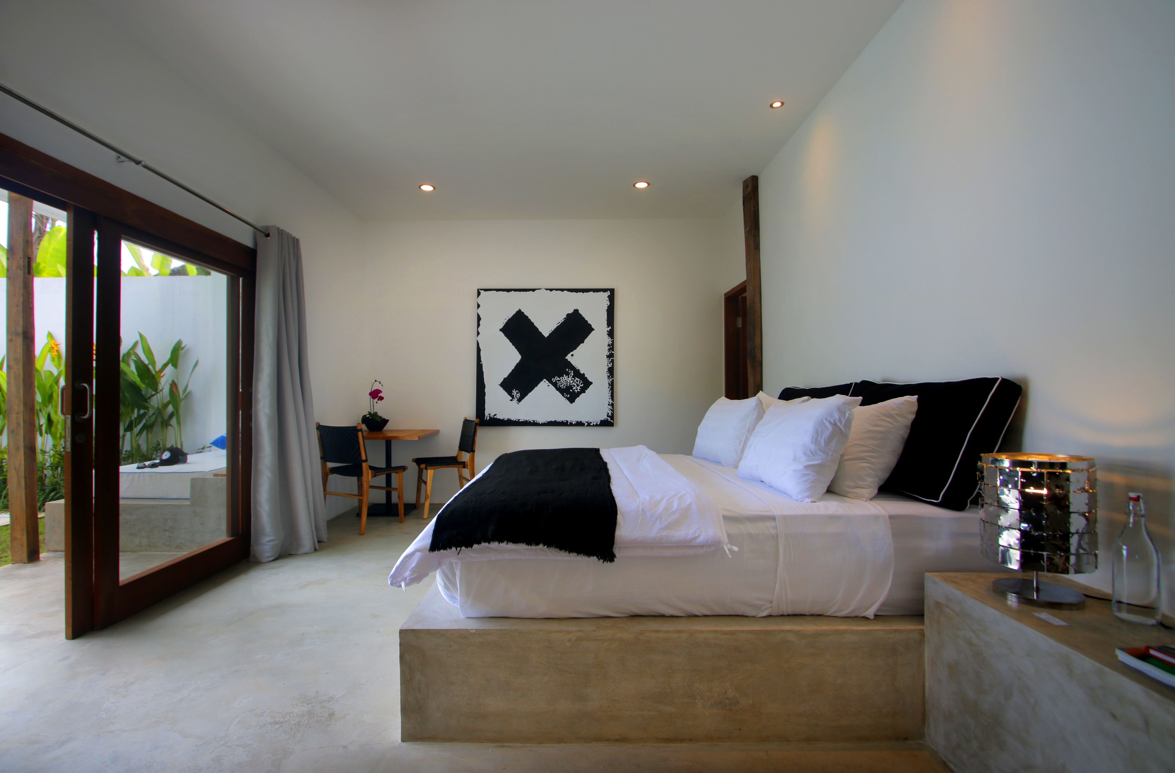 Une chambre moderne avec un grand lit, un bureau et une vue sur la verdure environnante.