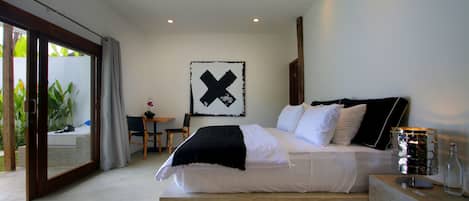 Une chambre moderne avec un grand lit, un bureau et une vue sur la verdure environnante.