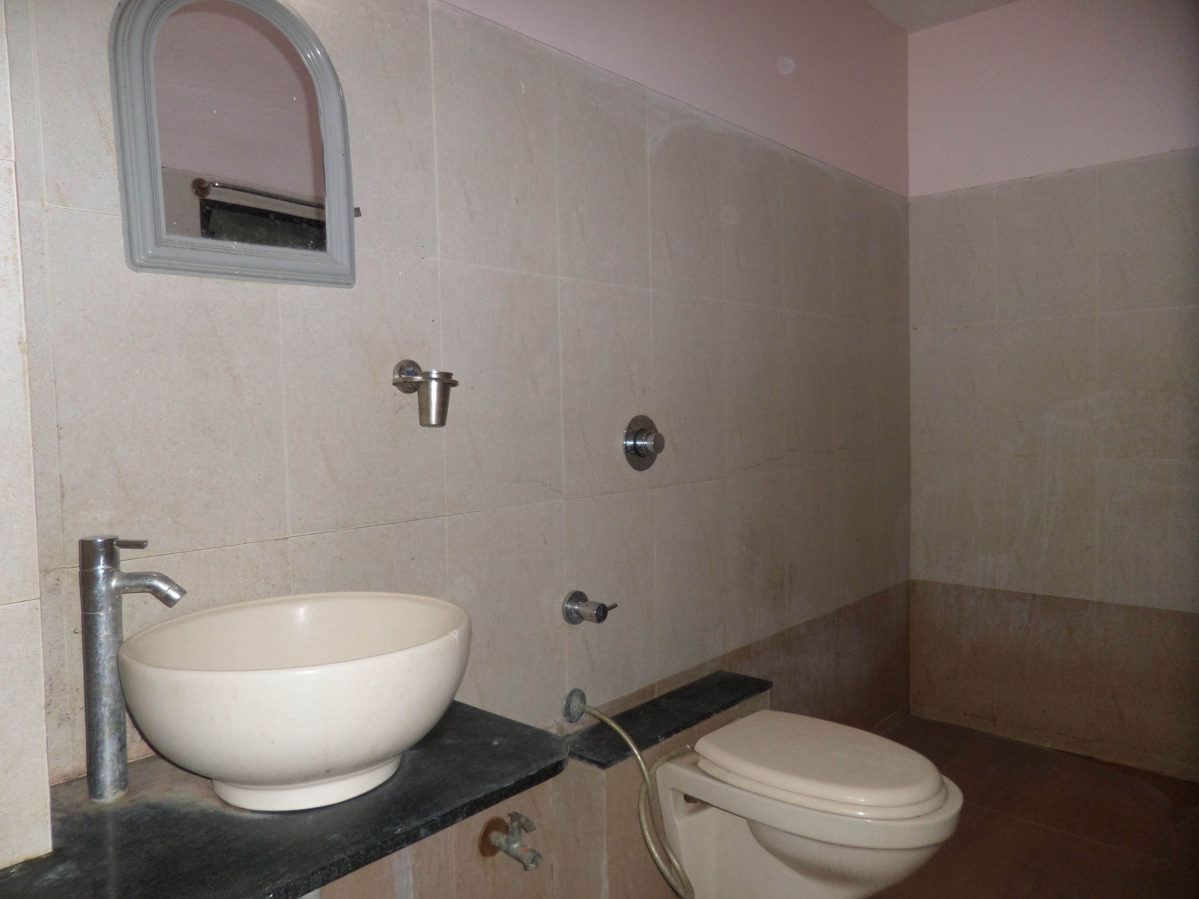 A bathroom with a sink, toilet, and a mirror.