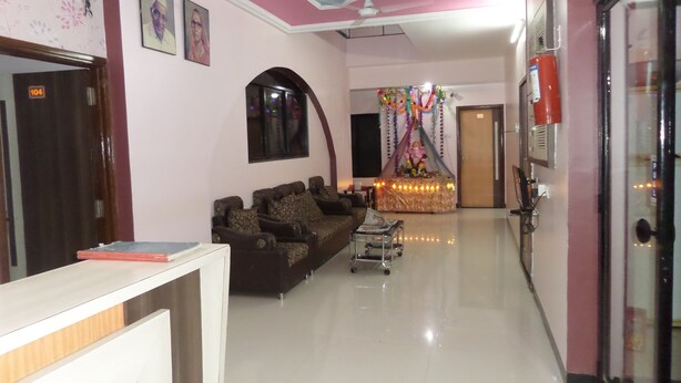 A reception area with a sofa, a desk, and a cart. - Hotel Amit Plaza (Dhule)