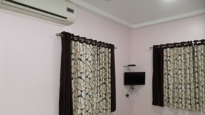 A room with a bed, an air conditioner, and a mounted TV. - Hotel Amit Plaza (Dhule)