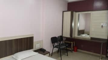 Habitación de hotel con dos camas, un escritorio, una silla, un espejo y un cubo de basura rojo.