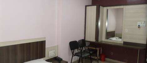 A hotel room with two beds, a desk with a chair, a mirror, and a red trash bin.
