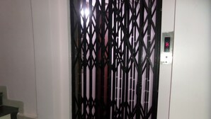 A staircase leading to a room with a metal gate and a digital clock on the wall. - Hotel Amit Plaza (Dhule)