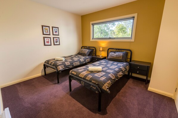 Un dormitorio con dos camas, una ventana y una mesita de noche con lámpara.