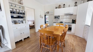 Une cuisine de taille réduite avec des meubles blancs, une table à manger en bois et un four à micro-ondes.