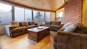 Un salon spacieux avec un plafond en bois, de grandes fenêtres et un mur en briques.