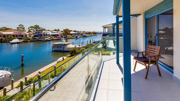 Un balcón con vistas a un puerto deportivo, una silla y una barandilla de cristal.