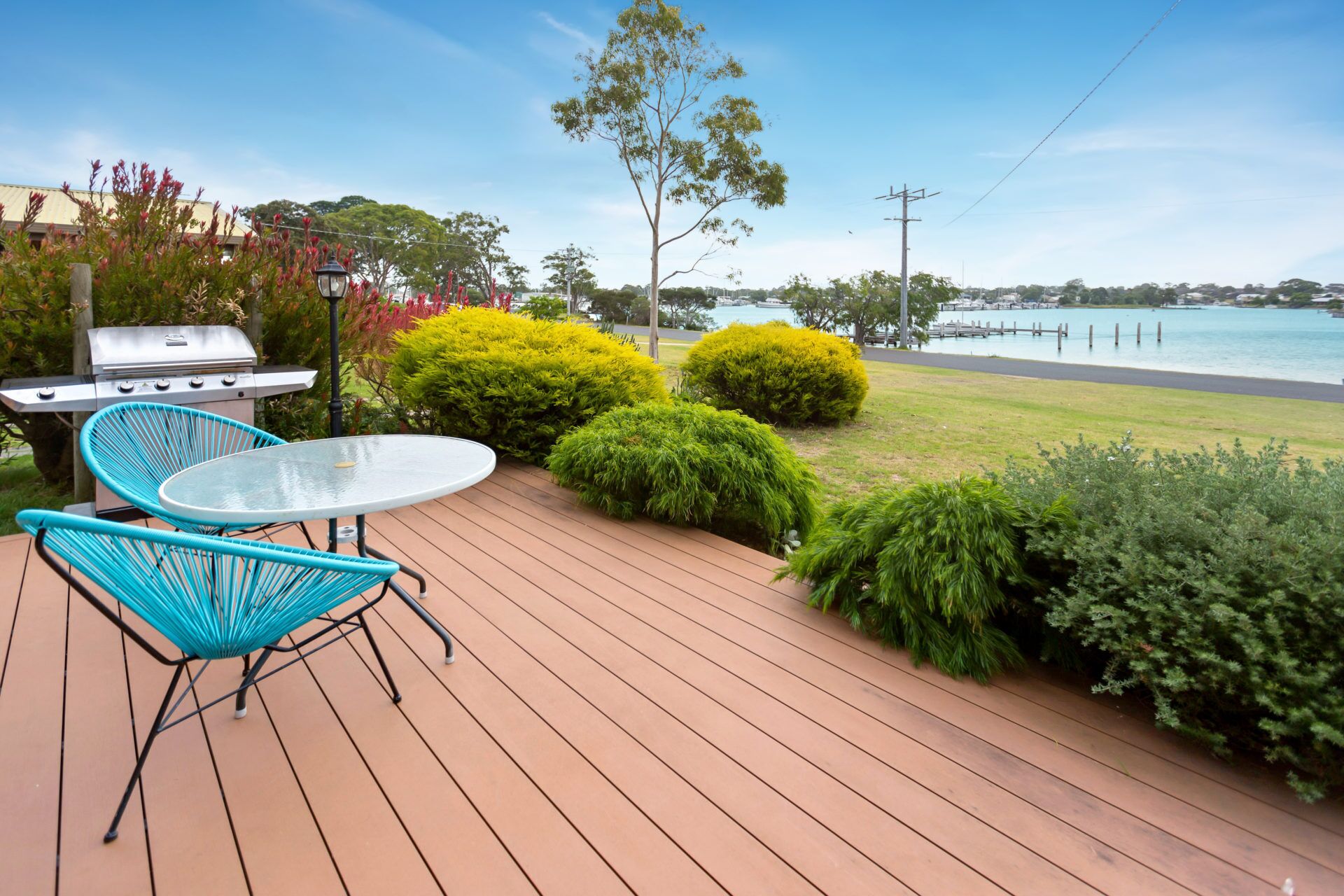 A deck with a grill, two chairs, and a table.