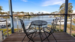 A balcony with a metal table and chairs overlooking a lake with boats.