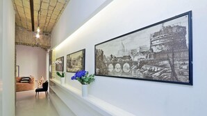 Ein Flur mit gerahmten Schwarz-Weiß-Fotos an der Wand, einer weißen Vase mit blauen Blumen und einem Sofa mit einer sternförmigen Lichtdekoration.
