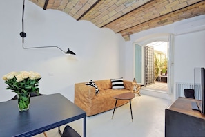 A modern living room with a sofa, a coffee table, and a vase of flowers.