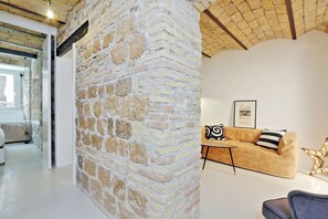 A modern living room with a stone wall, a sofa, and a framed picture.
