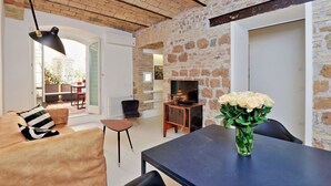 Ein modernes Wohnzimmer mit Steinwand, einer Couch, einem Couchtisch, einem Fernseher und einer Blumenvase.