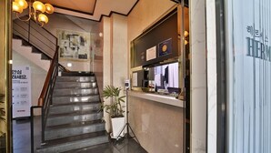 Un escalier menant à un espace d’accueil doté d’un écran numérique et agrémenté d’une plante en pot.