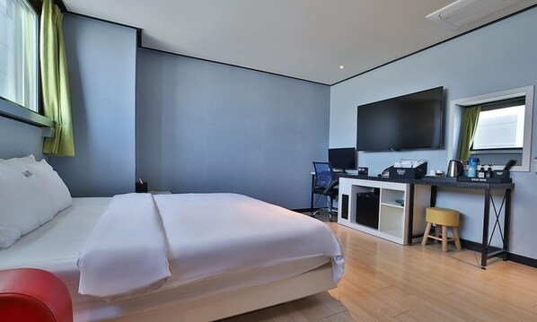 A hotel room with a bed, desk, chair, and a television.