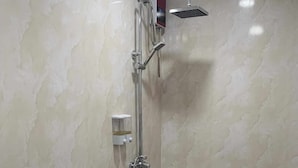 A bathroom with a toilet, a shower with a handheld showerhead, and a wall-mounted control panel. - Maine City (Manila)