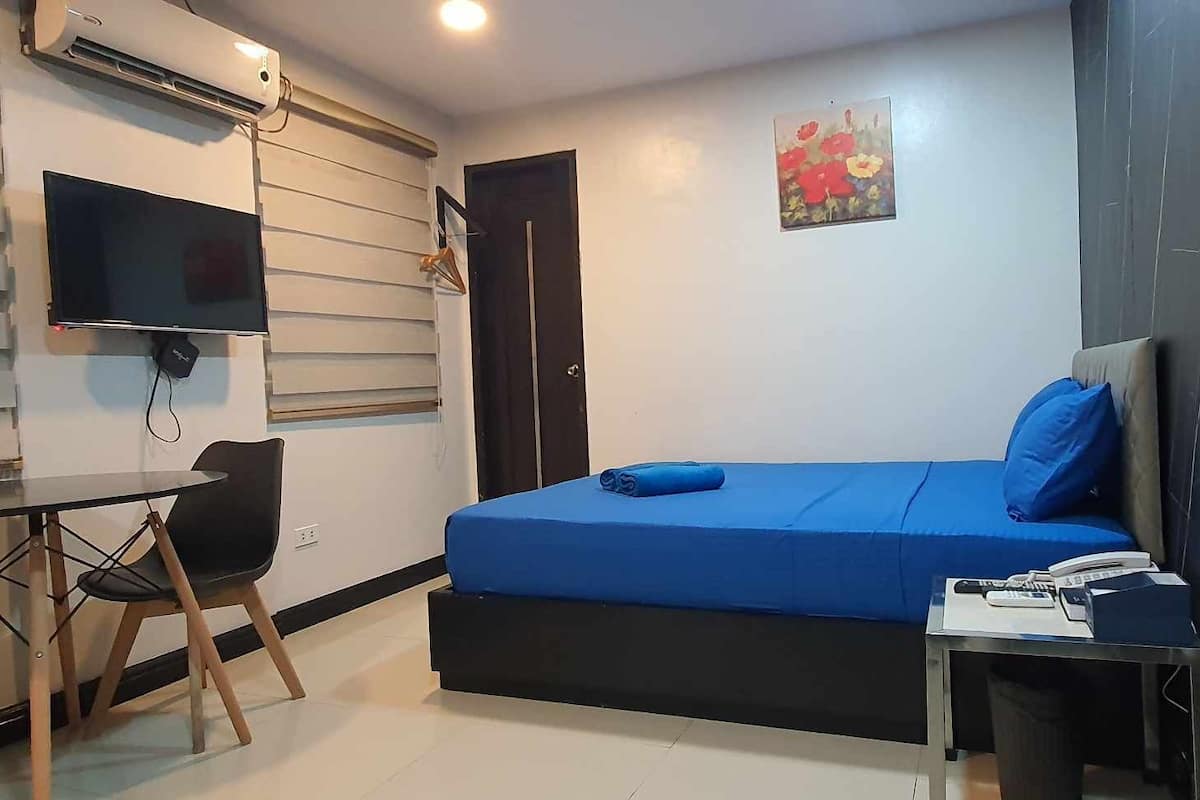 A small, modern room with a bed, a desk, and a chair.