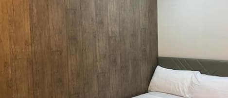 Una habitación de hotel con una pared de acento de madera, una cama con ropa blanca y un cabecero.