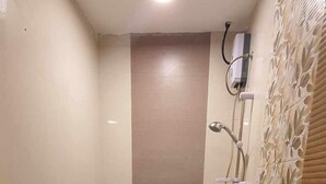 A small, modern bathroom with a toilet, a shower, and a wall-mounted toilet paper holder. - Maine City (Manila)