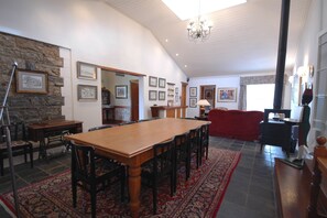 A spacious dining area with a wooden table and chairs, a red sofa, and a stone accent wall.