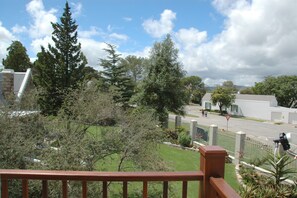 A residential area with a street, trees, and a building with a white facade.