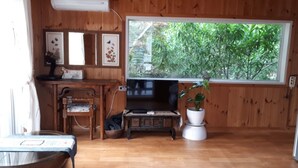 Interior de madera con un ventanal grande, una mesa de madera, una silla y una planta en maceta.