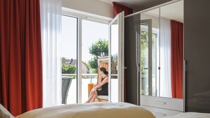 A hotel room with a bed, a wardrobe, and a sliding glass door leading to an outdoor area. - Hotel Nora (Bad Krozingen)