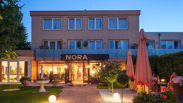 A hotel with a 'NORA' sign, outdoor seating, and a well-maintained garden. - Hotel Nora (Bad Krozingen)