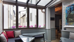 Een modern interieur met een zitgedeelte met een bank, een kleine tafel en uitzicht door grote ramen.