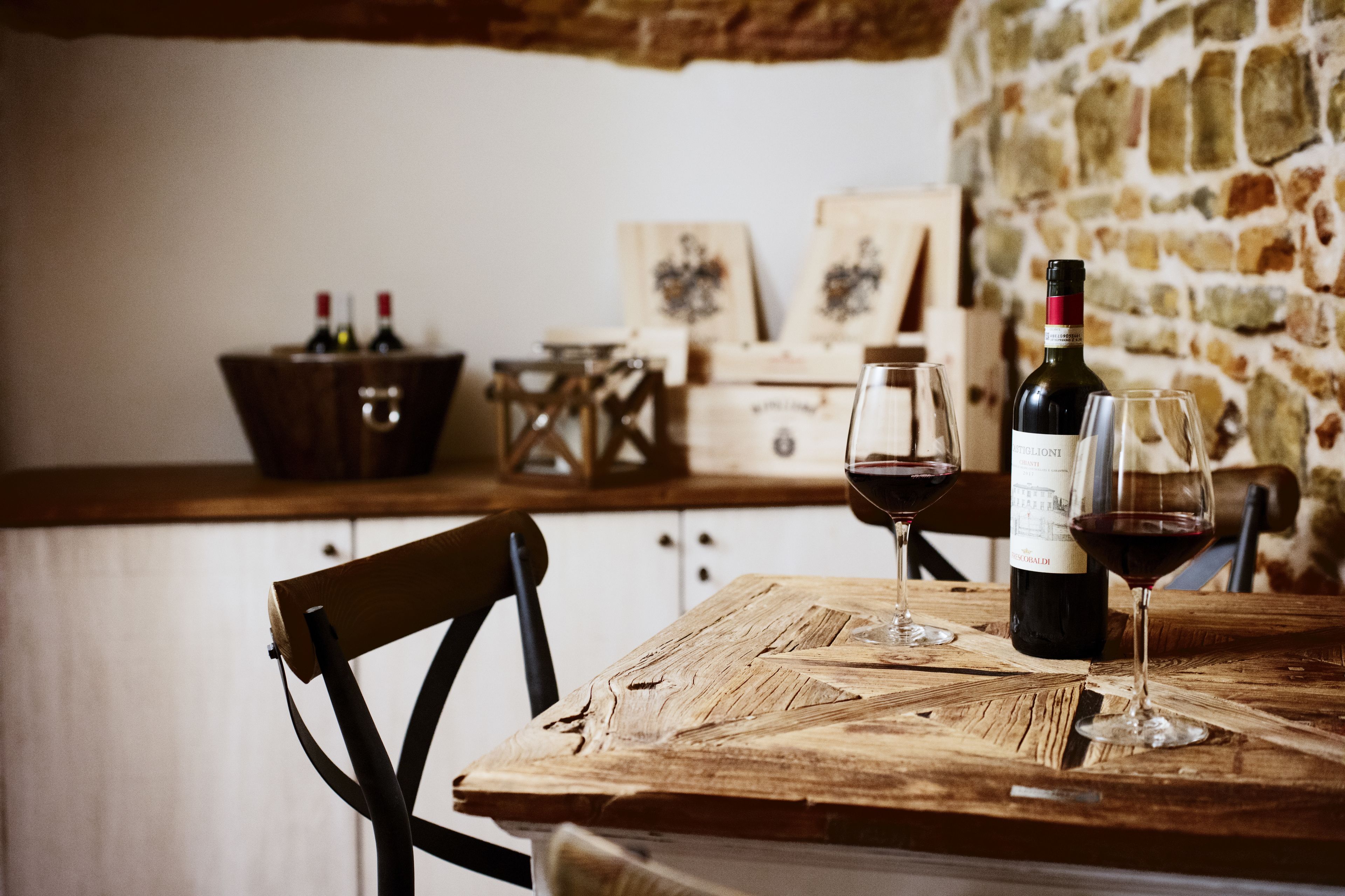 A rustic wooden table with two wine glasses and a bottle of wine.