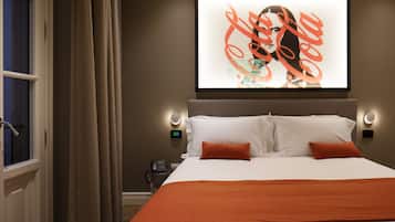 Hotelkamer met een bed, twee kussens, een deken, een wanddecoratie, een nachtkastje met telefoon, en een raam met gordijnen.