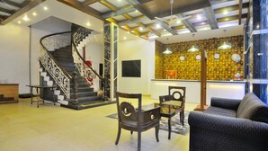 A spacious living area with a curved staircase, a reception desk, and a seating area with a sofa and chairs. - Hotel Maya Cottage (New Delhi)
