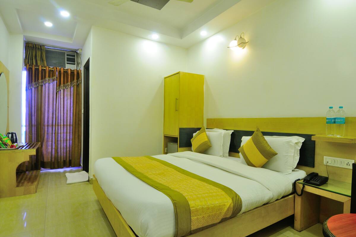 A hotel room with a bed, a desk, a chair, a wardrobe, and a bathroom visible through a curtain.