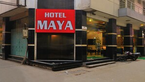 A hotel named "Hotel Maya" with a prominent red sign, a glass facade, and a balcony on the upper floor. - Hotel Maya Cottage (New Delhi)