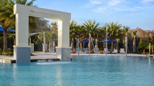 A pool area with a modern arch structure, lounge chairs, and palm trees. - Aco238645 - Sonoma Resort - 7 Bed 6.5 Baths Villa (Kissimmee)