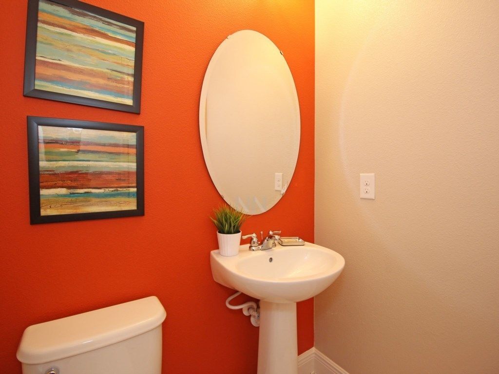 Une salle de bain avec des toilettes blanches, un lavabo blanc et deux tableaux encadrés accrochés au mur.