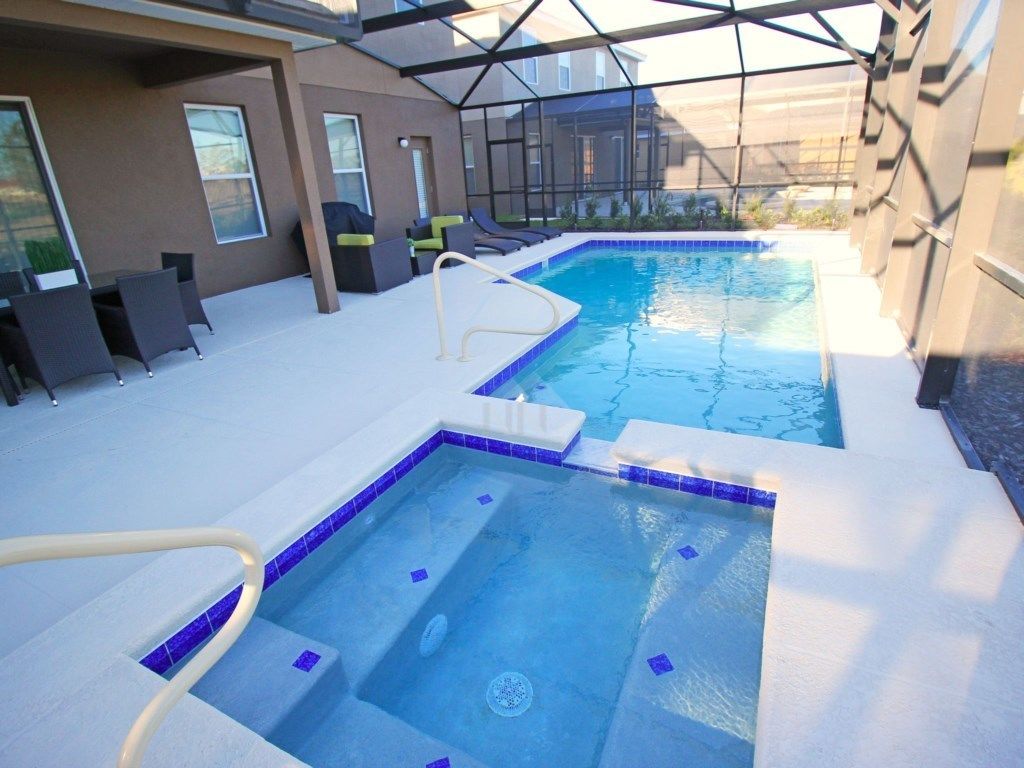 A rooftop pool area with two separate pools, a lounge area with chairs, and a covered section with a glass ceiling.