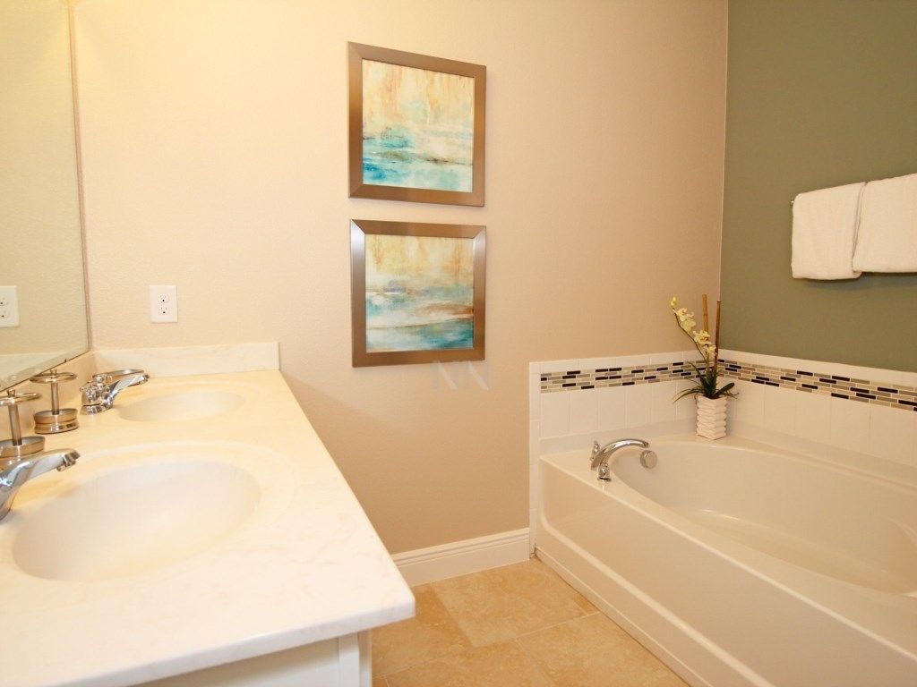 Une salle de bain avec deux lavabos, une baignoire et deux tableaux encadrés au mur.