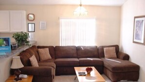 A living room with a brown sectional sofa, a small wooden table, and a lamp. - Ahr104 - Westbury - 4 Bed 3 Baths Villa (Davenport)