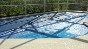 A swimming pool with a blue cover, surrounded by a glass enclosure with a view of trees. - Ahr104 - Westbury - 4 Bed 3 Baths Villa (Davenport)