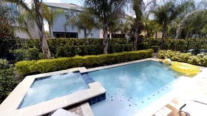 A rectangular pool with a hot tub section, surrounded by a hedge and palm trees. - Aco231263 - The Encore Club Resort - 6 Bed 6.5 Baths Villa (Kissimmee)